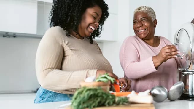 Two people cooking together and sharing a laugh