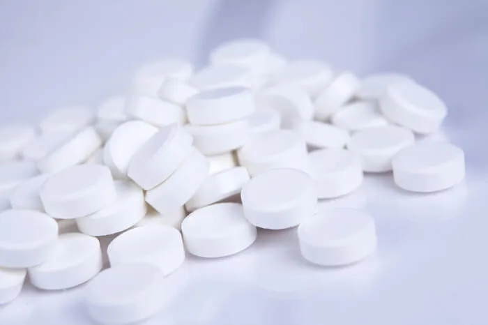 White pills in a pile on white/grey table