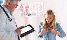 A young female patient describes her acid reflux symptoms to her doctor.