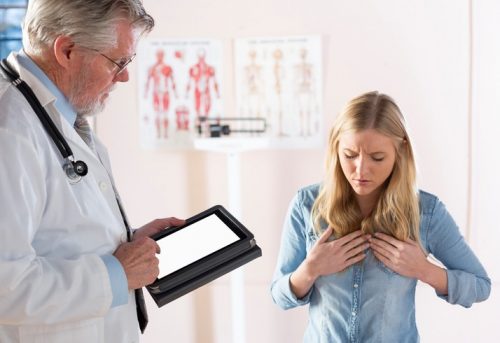 A young female patient describes her acid reflux symptoms to her doctor.